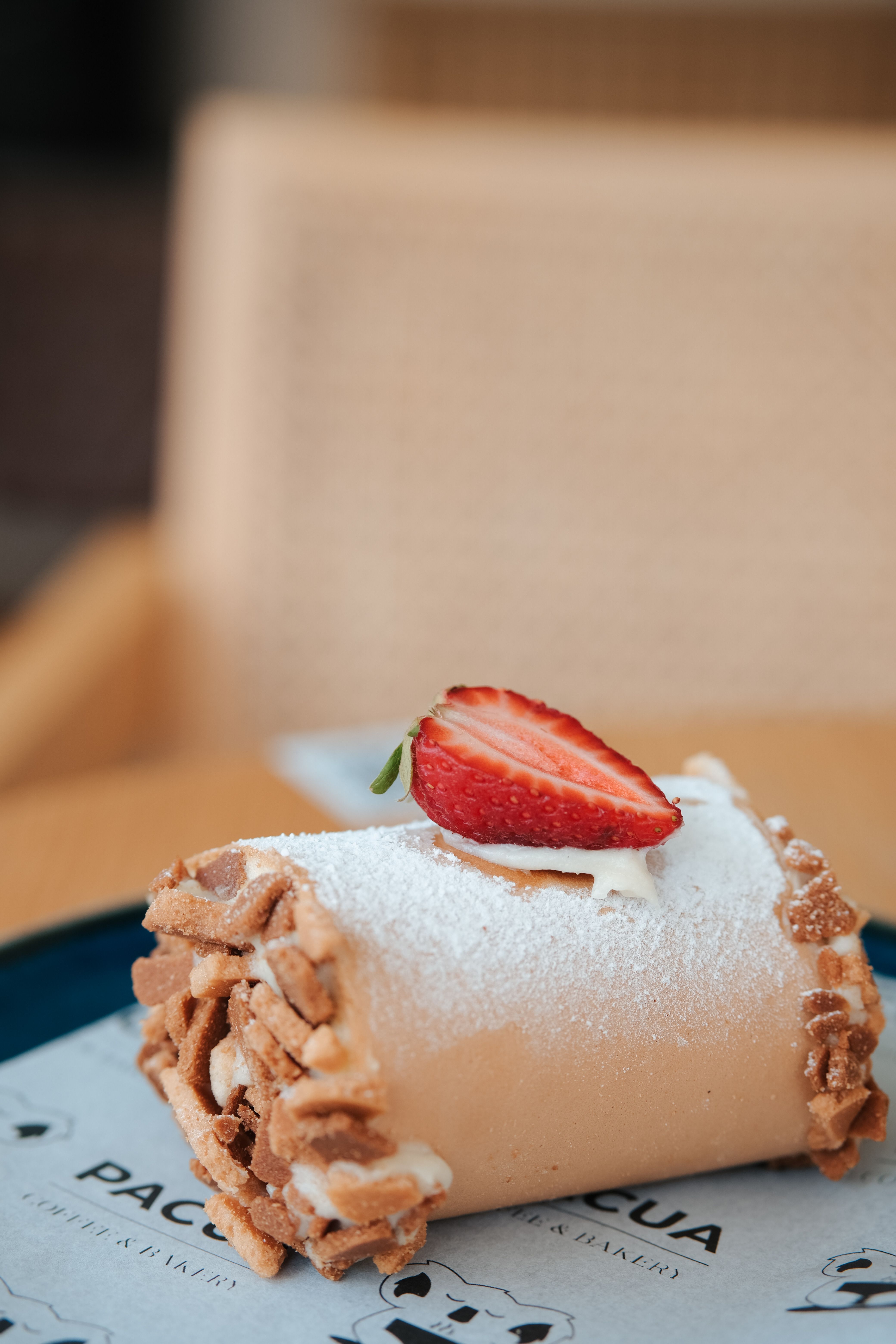 Close-up of a cream roll cake with strawberry slice on top, perfect for dessert enthusiasts.