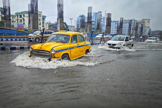 A yellow taxi battles flooding on urban streets in Kolkata, India. Heavy rain impacts city traffic.