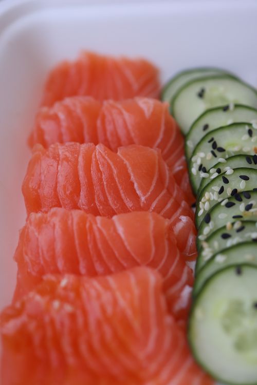 Free Close-up of fresh salmon slices and cucumber with sesame seeds, perfect for sushi lovers. Stock Photo