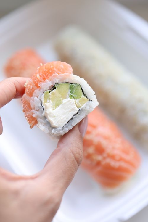 Free Gourmet sushi roll with seafood and avocado held by hand, showcasing texture and freshness. Stock Photo