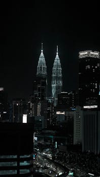 Stunning night skyline featuring the illuminated Petronas Towers in Kuala Lumpur, Malaysia.