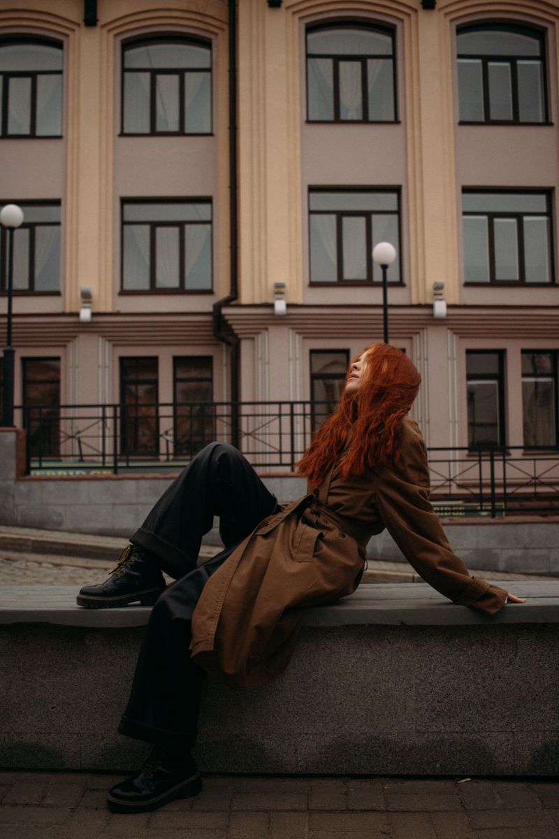 A Woman in Brown Trench Coat Sitting on the Ledge · Free Stock Photo