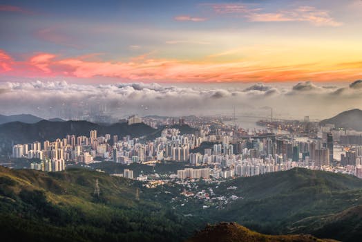 从空中俯瞰，城市天际线令人惊叹，四周环绕着山脉，映衬着色彩缤纷的日落天空