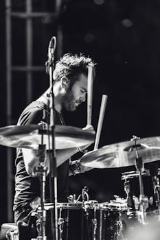 Black and white photo of a drummer performing passionately during a live music concert.