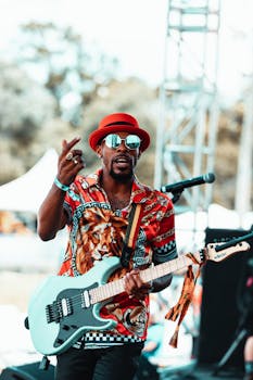 Energetic performer in colorful attire plays electric guitar at an outdoor concert.