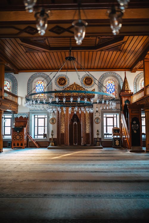 The interior of a mosque with wooden floors and chandeliers