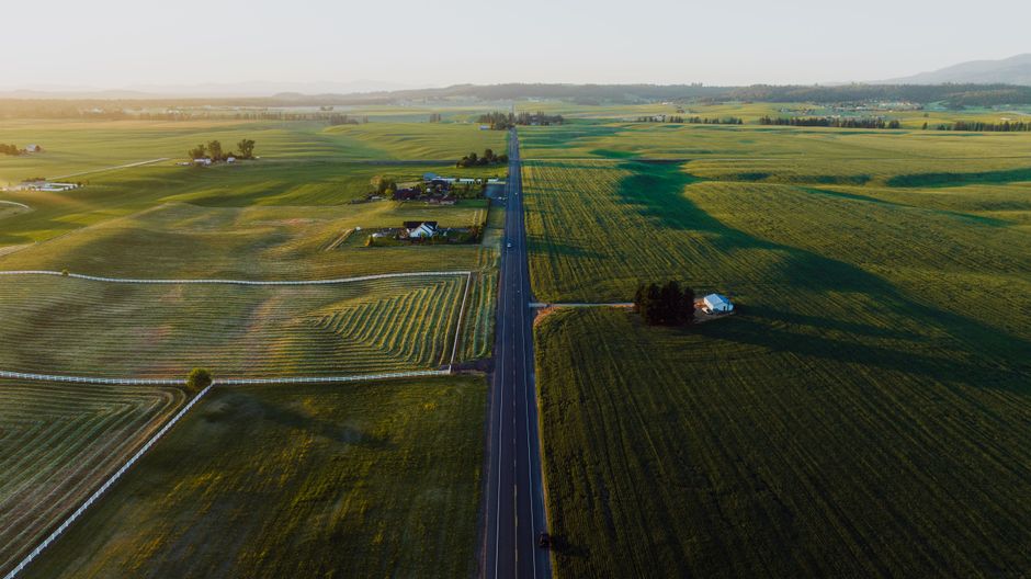 Aerial view of lush green fields and a country road in Spokane, WA, during daytime.