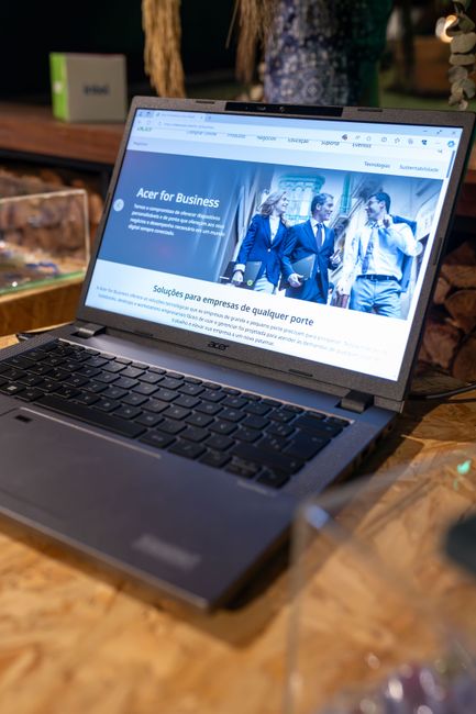 An open Acer laptop displaying a business webpage, set on a wooden desk indoors.