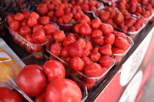 Free Close-up of ripe strawberries and tomatoes on display at a market, offering fresh produce. Stock Photo