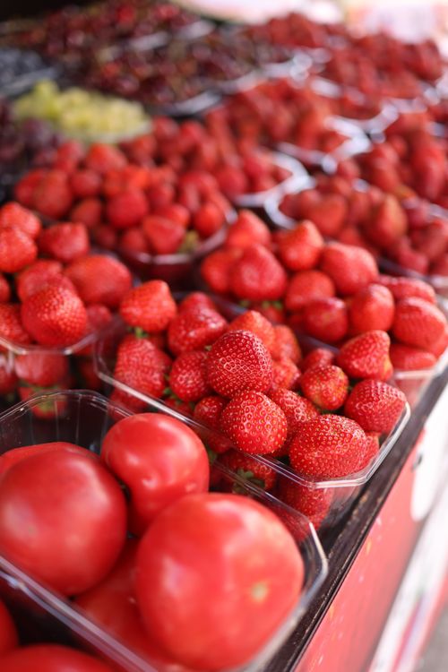 Free Vibrant strawberries and tomatoes on a market stall showcasing fresh produce. Stock Photo