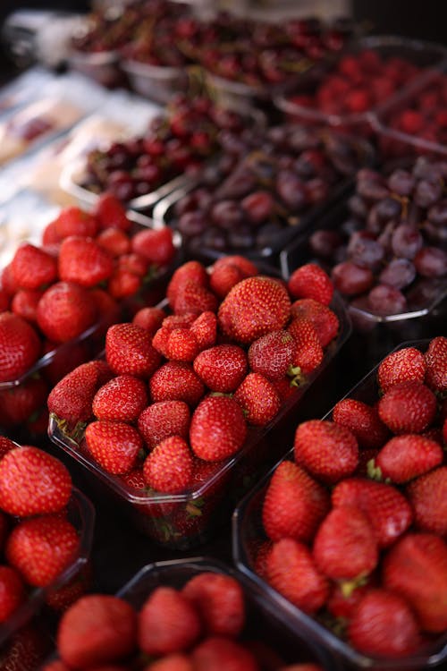 Free Strawberries and cherries are displayed at a market Stock Photo