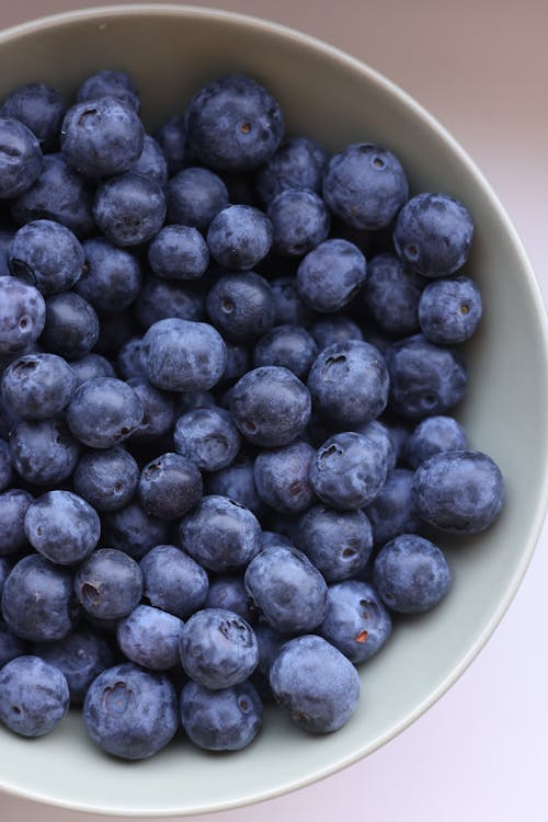 Blueberries in a bowl on a white surface