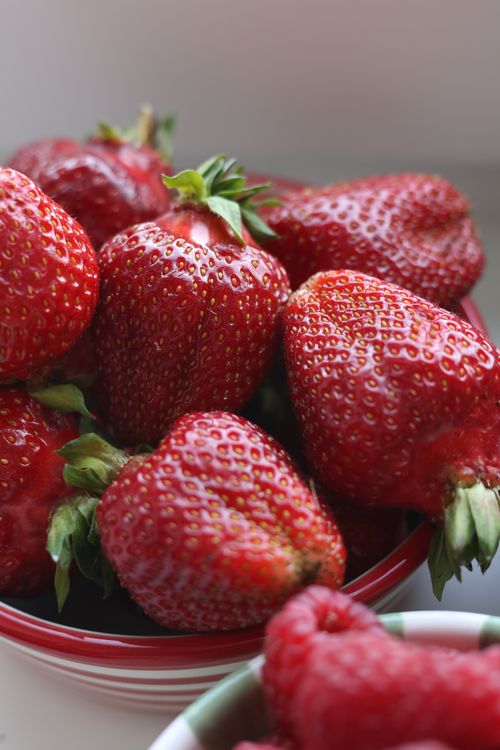 Free Vibrant close-up of fresh strawberries in a red bowl, capturing their juicy detail. Stock Photo
