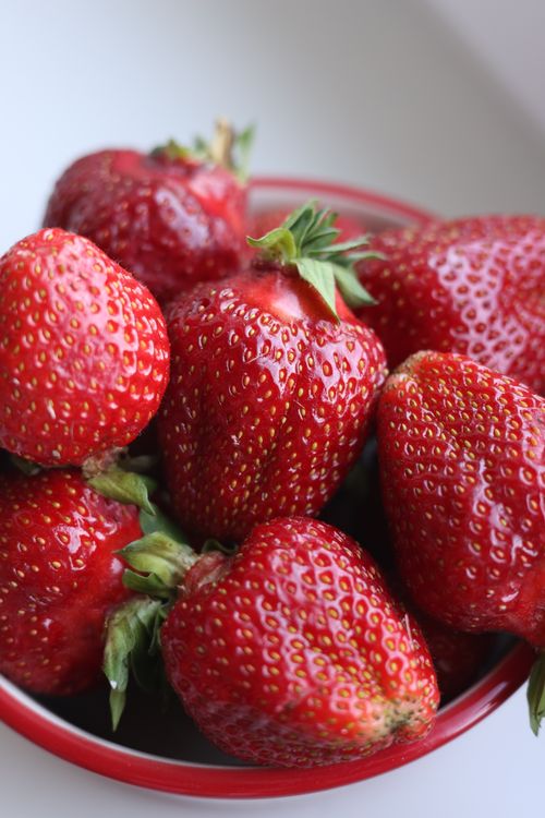 Free Fresh and juicy strawberries piled in a red bowl, showcasing vibrant colors and texture. Stock Photo