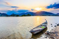 日落时分，山间湖景宁静，一叶孤舟展现着自然的静谧之美