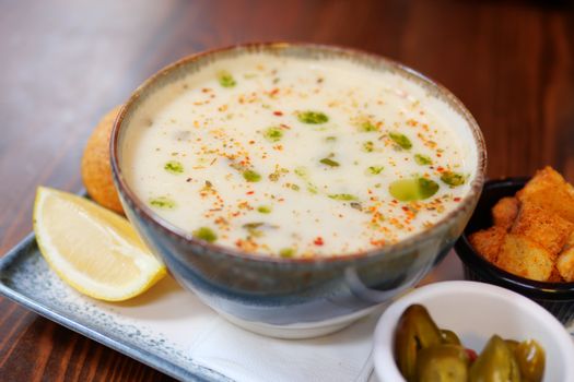 Delicious bowl of creamy soup garnished with herbs served with lemon, croutons, and jalapenos.