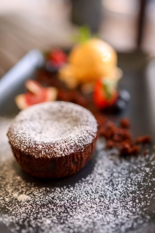 Free Artfully plated chocolate dessert dusted with powdered sugar, accompanied by fresh berries. Stock Photo