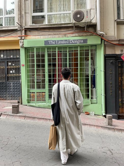 A man with shopping bags walks past a store in Istanbul, capturing the essence of urban shopping streets.