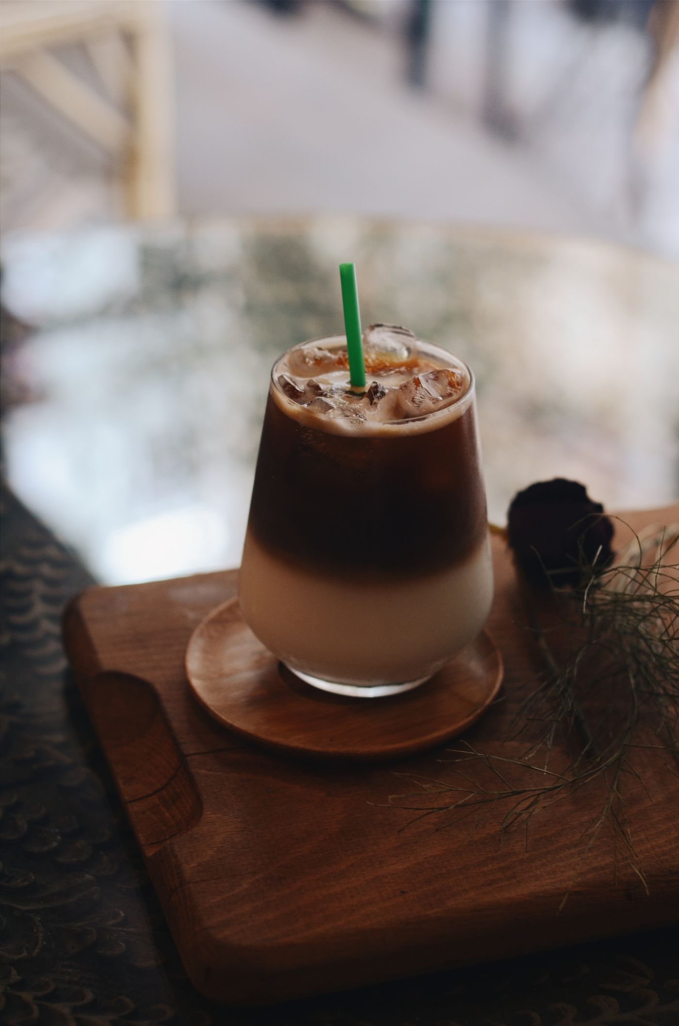 Vaso alto de café frío con leche y hielo, servido sobre una tabla de madera.