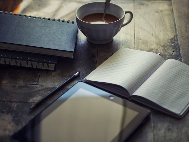 A close-up of a handwritten journal next to a modern laptop, symbolizing the blend of traditional diary-keeping with digital blogging