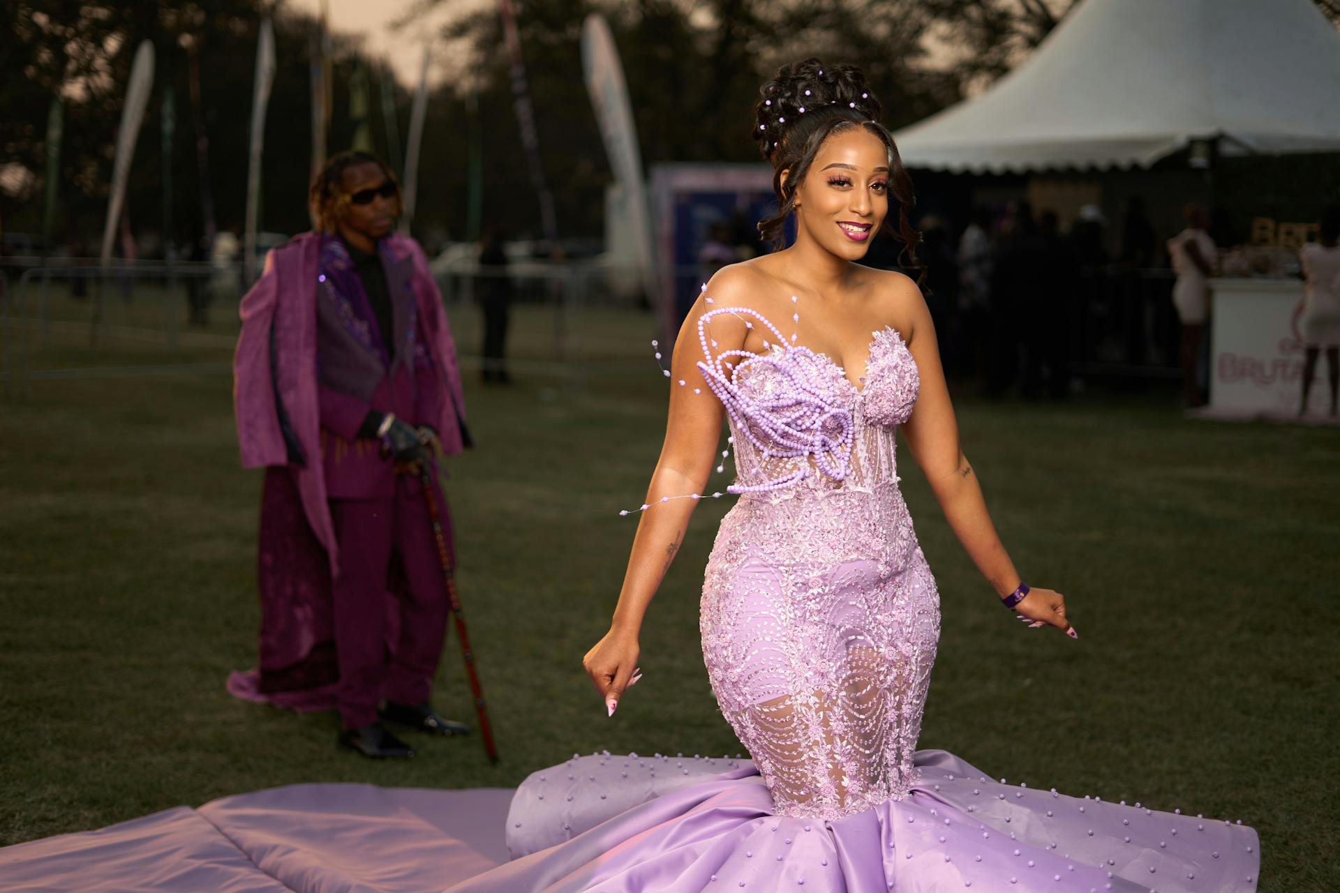 Models showcasing elegant fashion at Lusaka July. Vibrant purple and pink attire with unique designs.