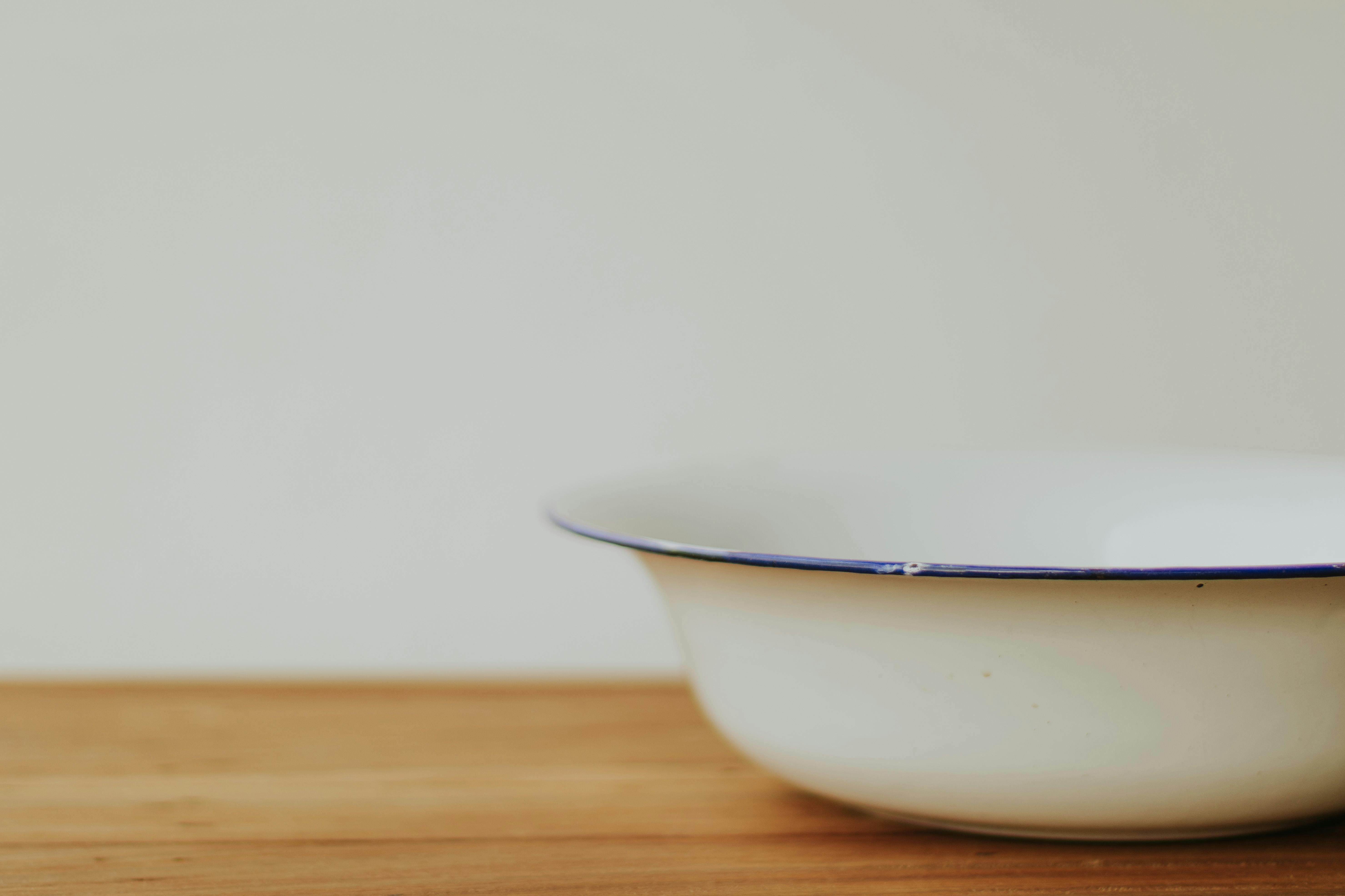 A minimalist porcelain bowl placed on a wooden surface, exuding simplicity and elegance.