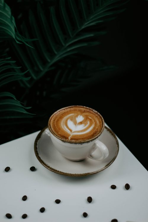 Free A cappuccino with latte art in a rustic cup surrounded by coffee beans. Stock Photo