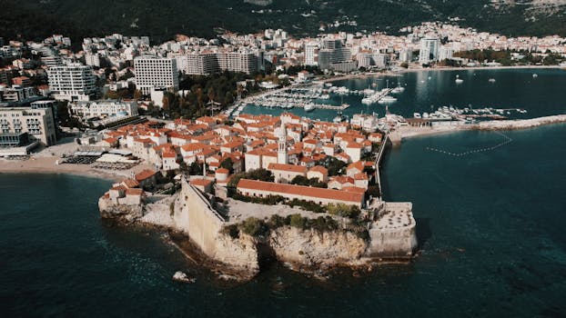 Stunning aerial view of Budva's historical old town, turquoise sea, and modern skyline.