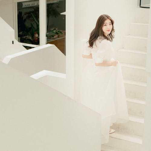 A woman in a white dress is standing on the stairs