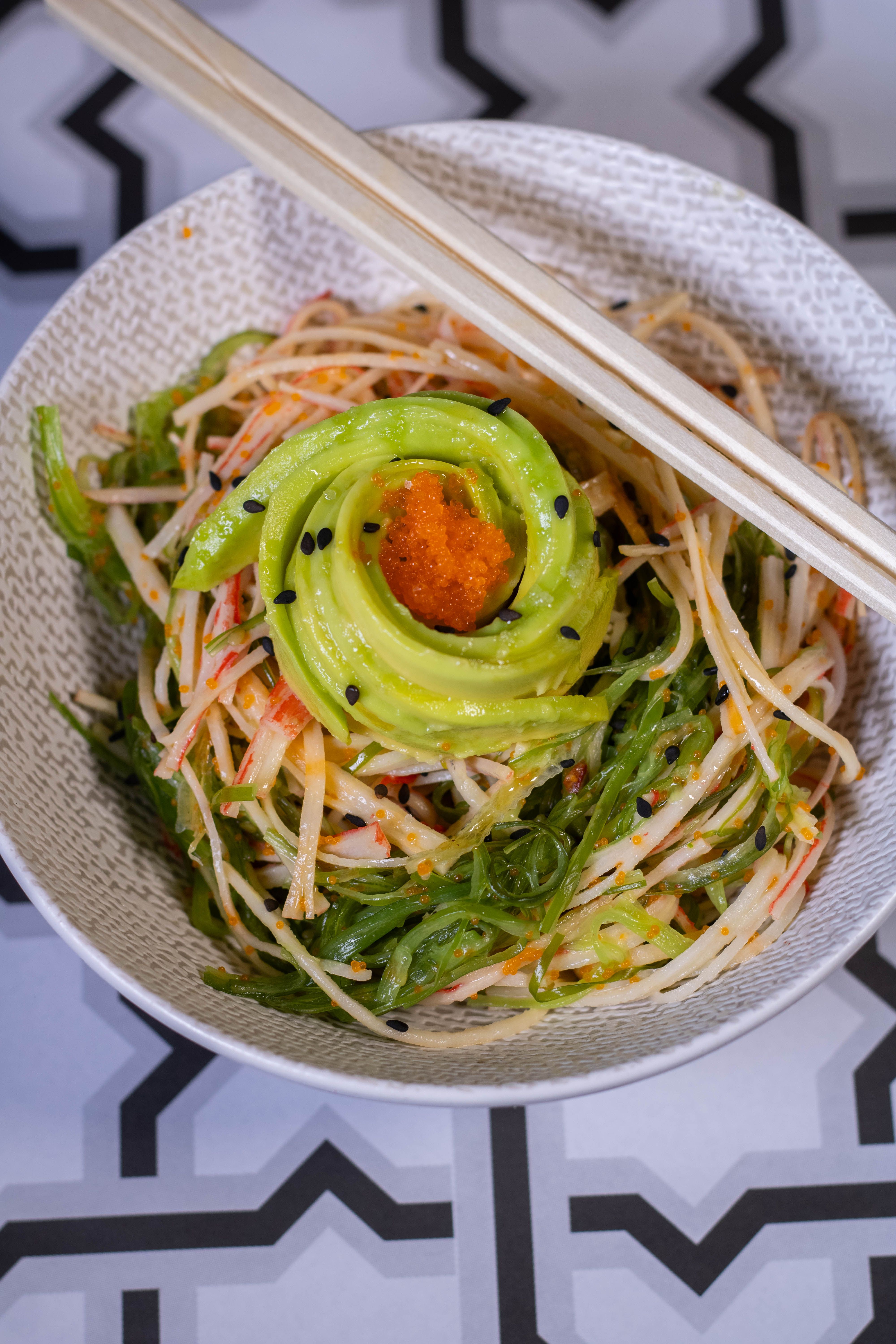 A bowl of shredded imitation crab kani salad tossed with julienned cucumber, mayo dressing, and a sprinkle of masago and sesame seeds.