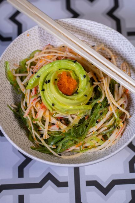 A bowl of shredded imitation crab kani salad tossed with julienned cucumber, mayo dressing, and a sprinkle of masago and sesame seeds.