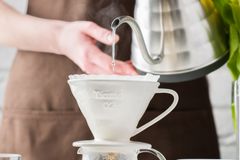 Close-up of coffee brewing with a pour-over method in a sunny kitchen setting.