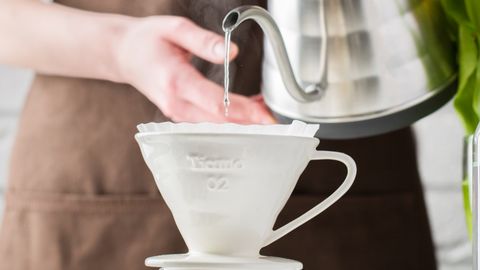 Close-up of coffee brewing with a pour-over method in a sunny kitchen setting.