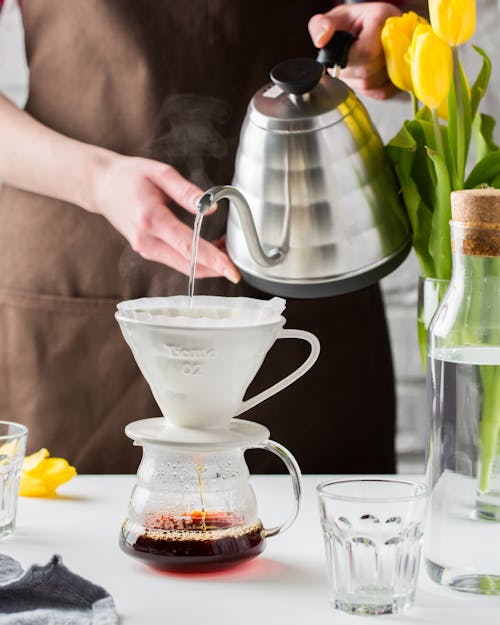 Foto Der Person, Die Wasser Auf Eine Tasse Gießt