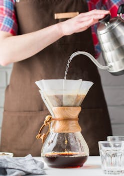 A close-up of a barista brewing coffee using a Chemex, highlighting the art of pour-over methods.