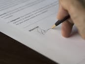 Selective Focus Photography of Person Signing on Paper