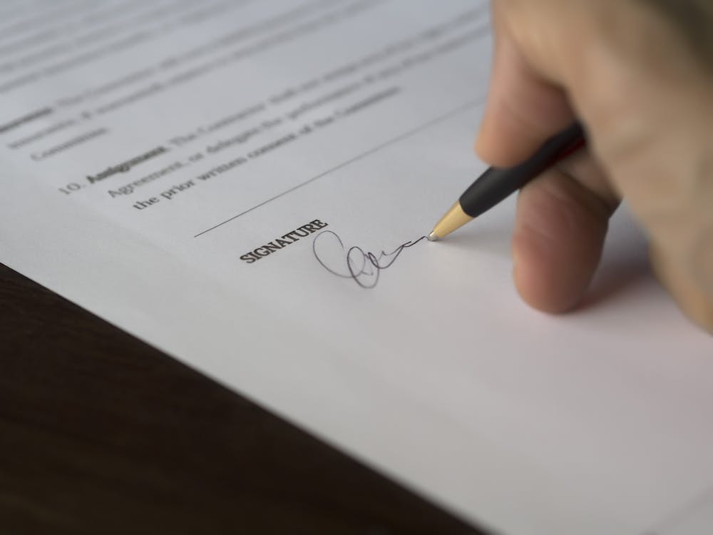 Selective Focus Photography of Person Signing on Paper