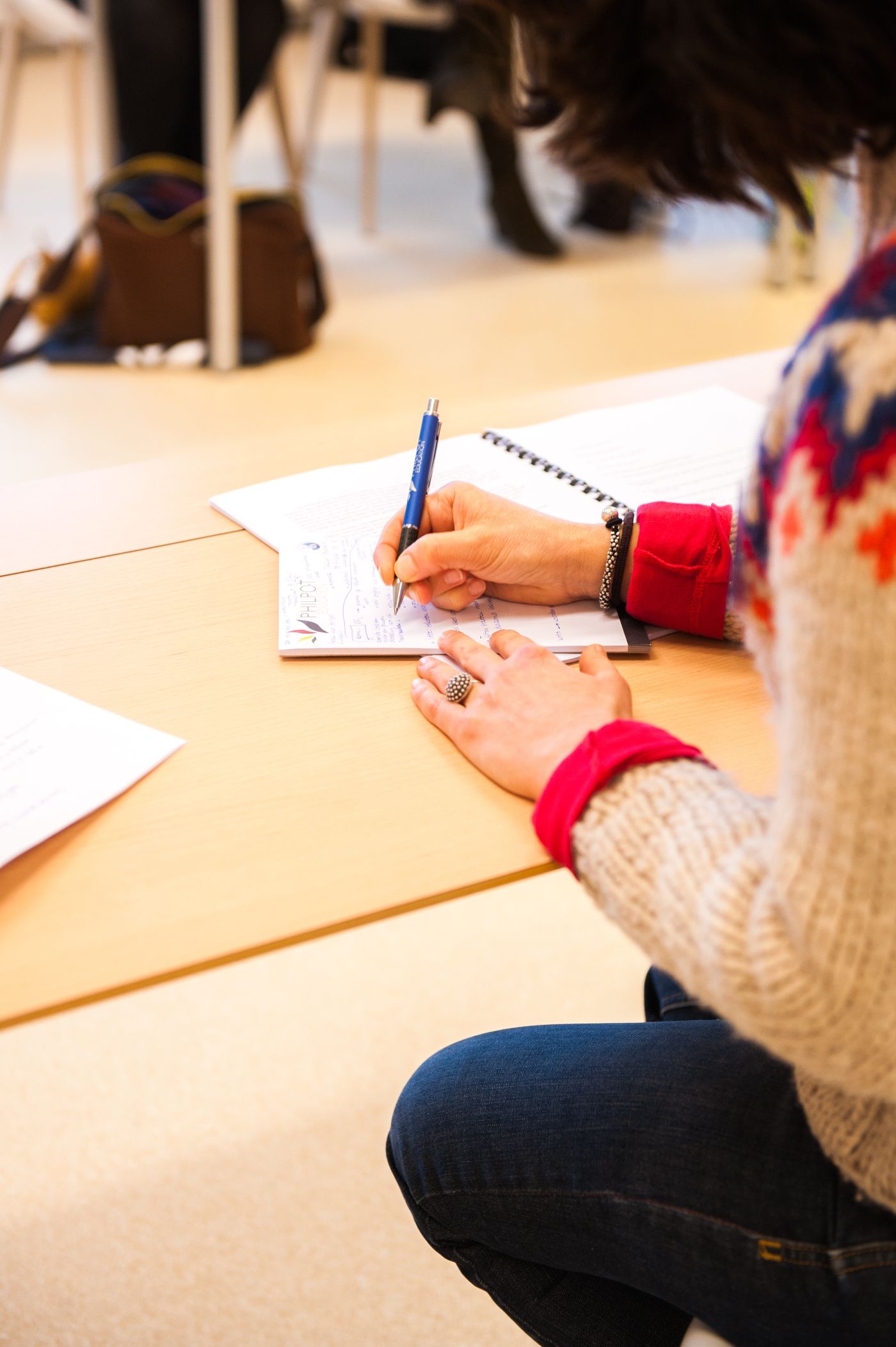 Une personne prend des notes au stylo bleu dans un carnet