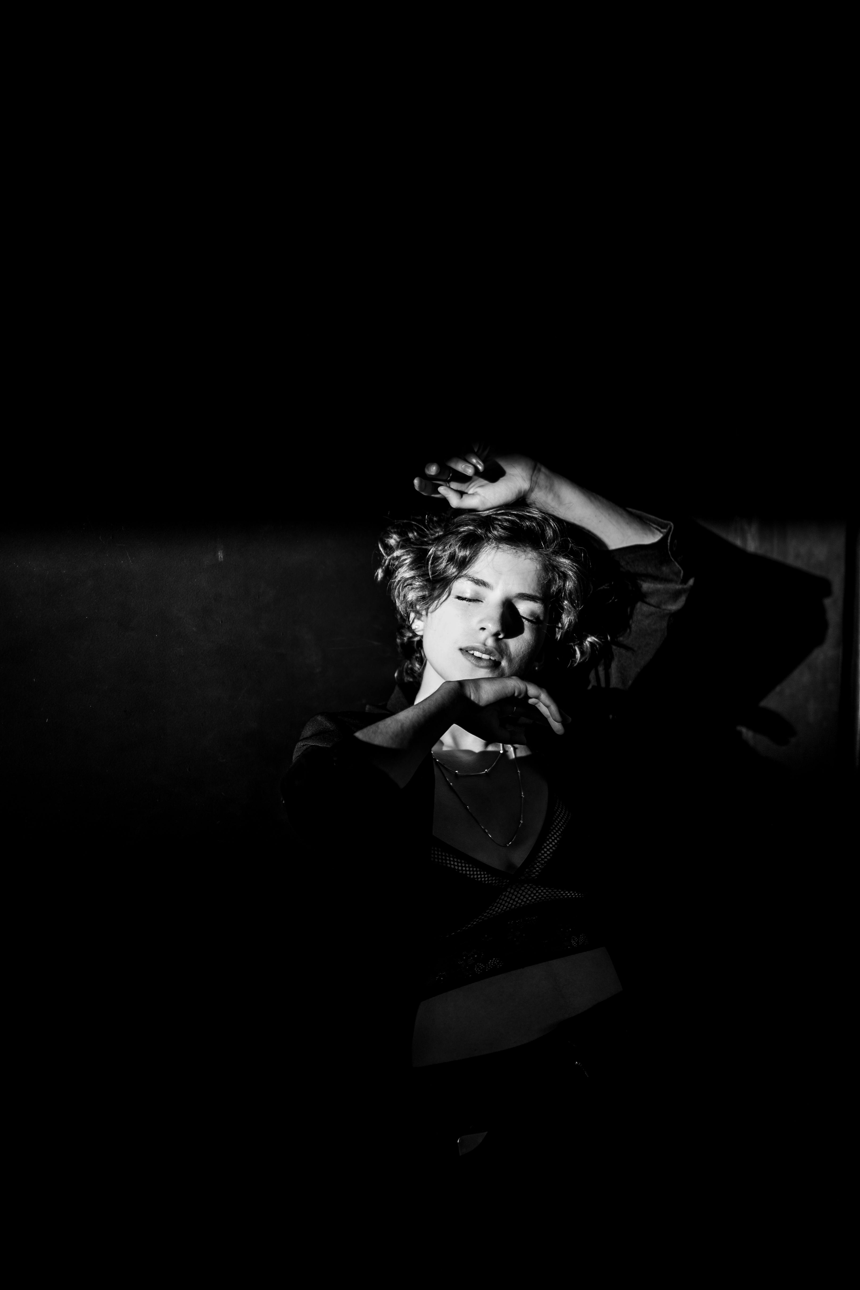 Black and white portrait of a woman with eyes closed, capturing dramatic light and shadow.