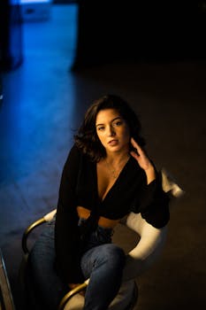 一位时尚女士穿着休闲装，在室内优雅地坐在扶手椅上摆姿势