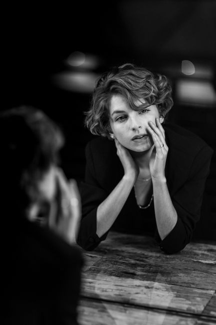 Black and white portrait of a woman gazing into a mirror thoughtfully.