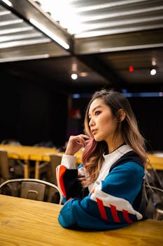 亚洲妇女在室内身穿时髦夹克，神情深思熟虑