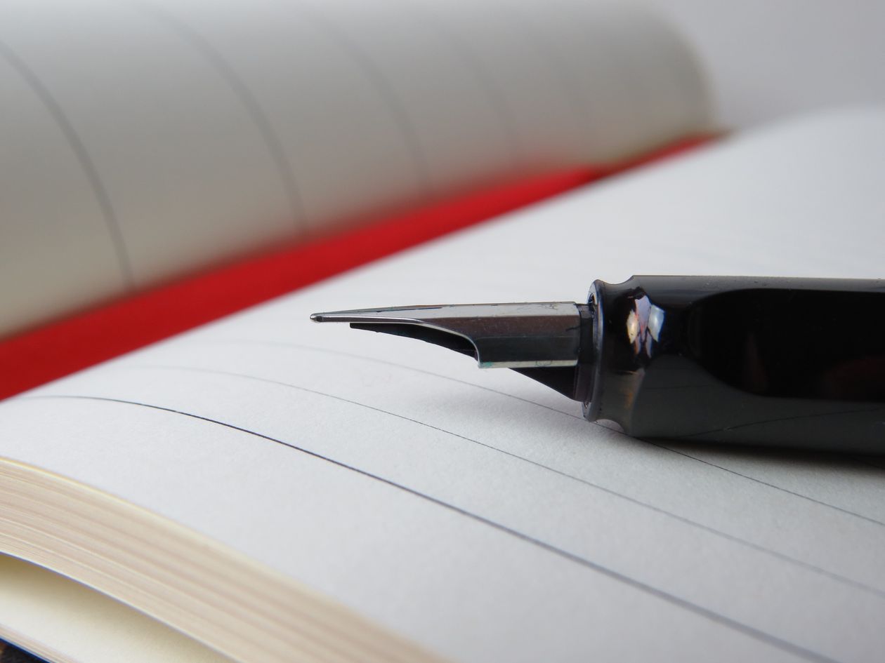 Fountain pen resting on an open lined notebook — fountain pen with bottled ink in use