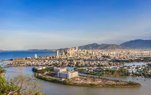 Free Aerial view of a coastal cityscape with mountains and sea on a sunny day. Stock Photo