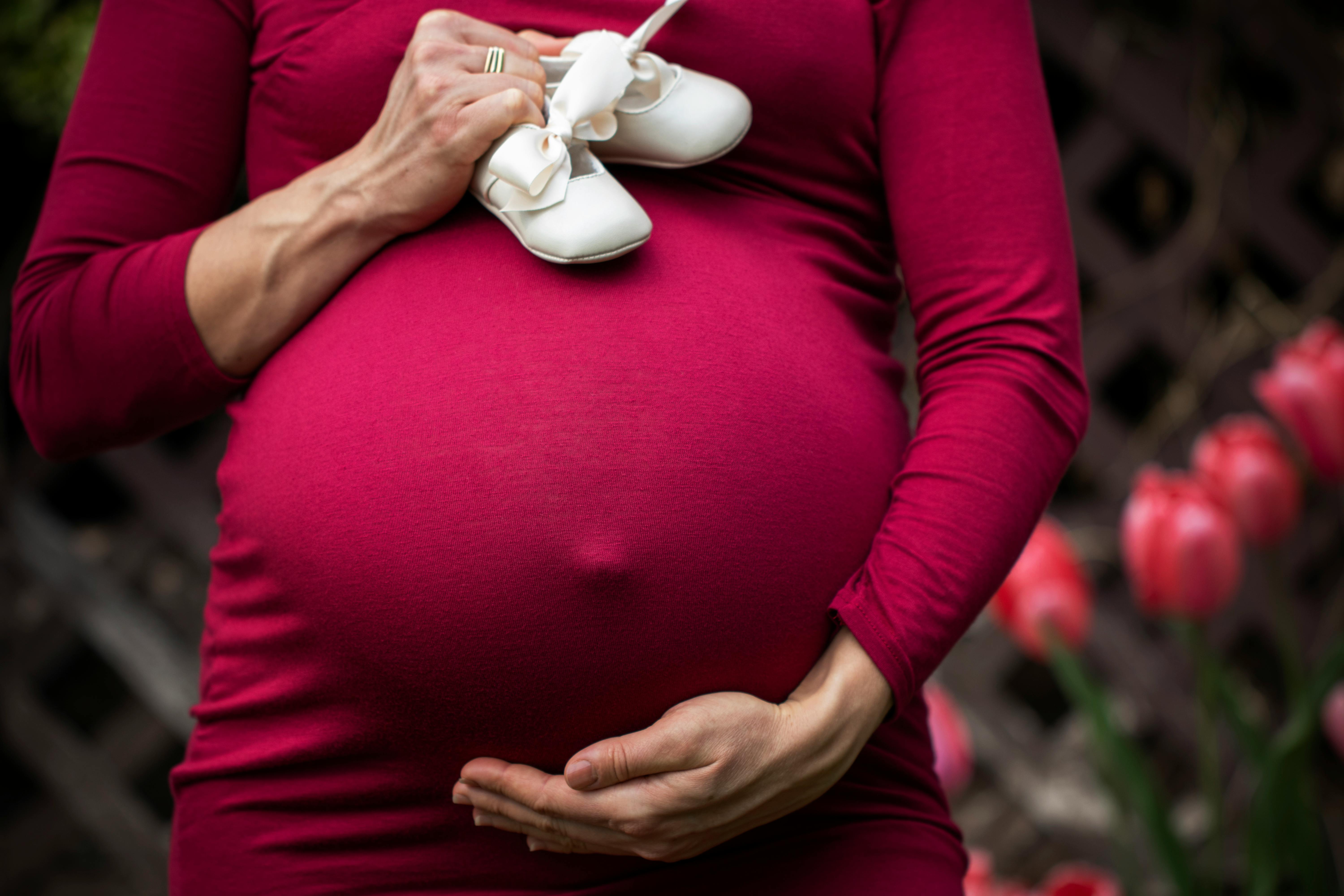 pregnant woman holding baby s shoes