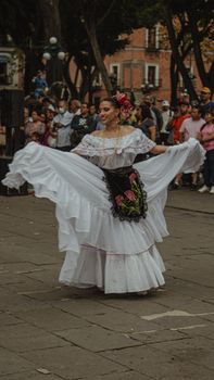 A woman performs a traditional Mexican dance in a vibrant street festival in Puebla, Mexico.