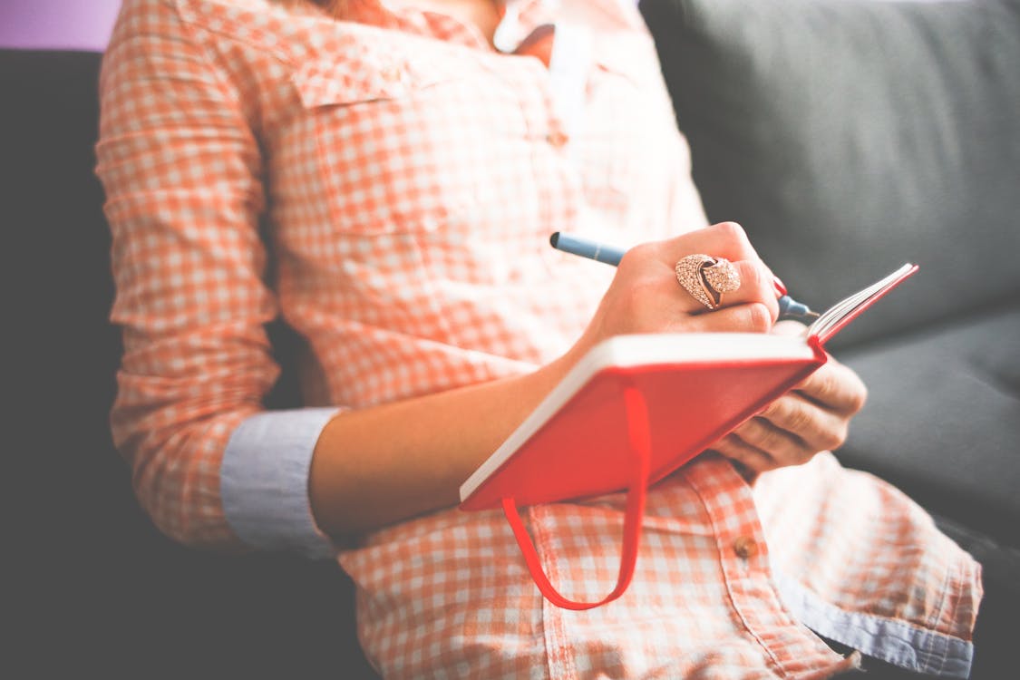 Free Person Writing on Red Notebook Stock Photo