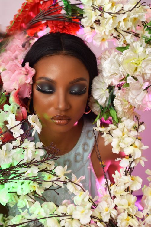 Free Stunning portrait of a woman with artistic makeup surrounded by colorful flowers. Stock Photo