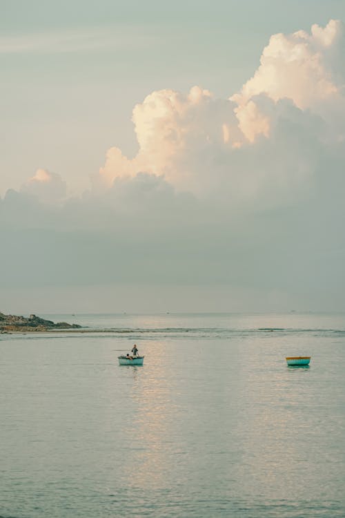 Two small boats in the ocean with clouds in the sky