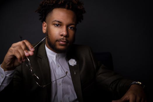 一位戴着眼镜、穿着优雅的黑人男子，肖像显得深思熟虑